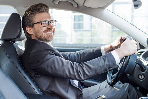 happy bearded ambassador holding steering wheel while driving car 