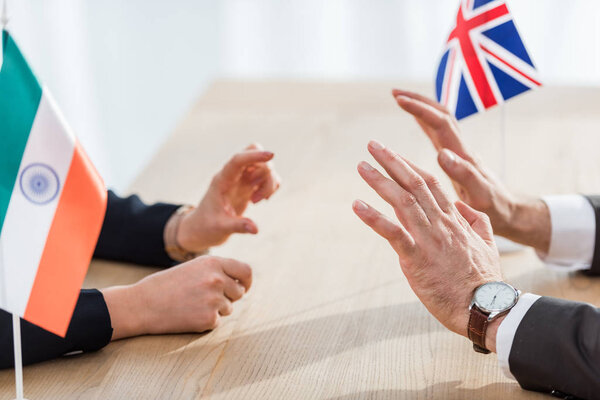 cropped view of diplomats gesturing near flags of india and united kingdom 