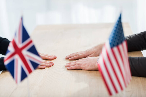 cropped view of diplomats near flags of america and united kingdom 