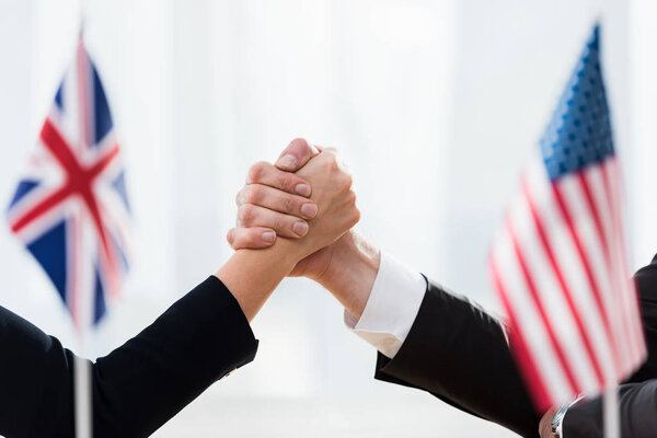 selective focus of diplomats shaking hands near flags of usa and united kingdom 