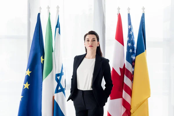 Diplomata Atraente Com Mãos Nos Bolsos Perto Bandeiras — Fotografia de Stock