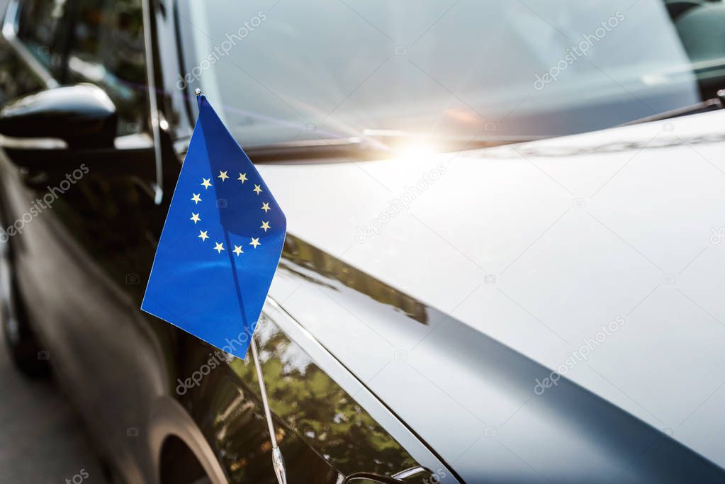 selective focus of european union flag near black shiny car 