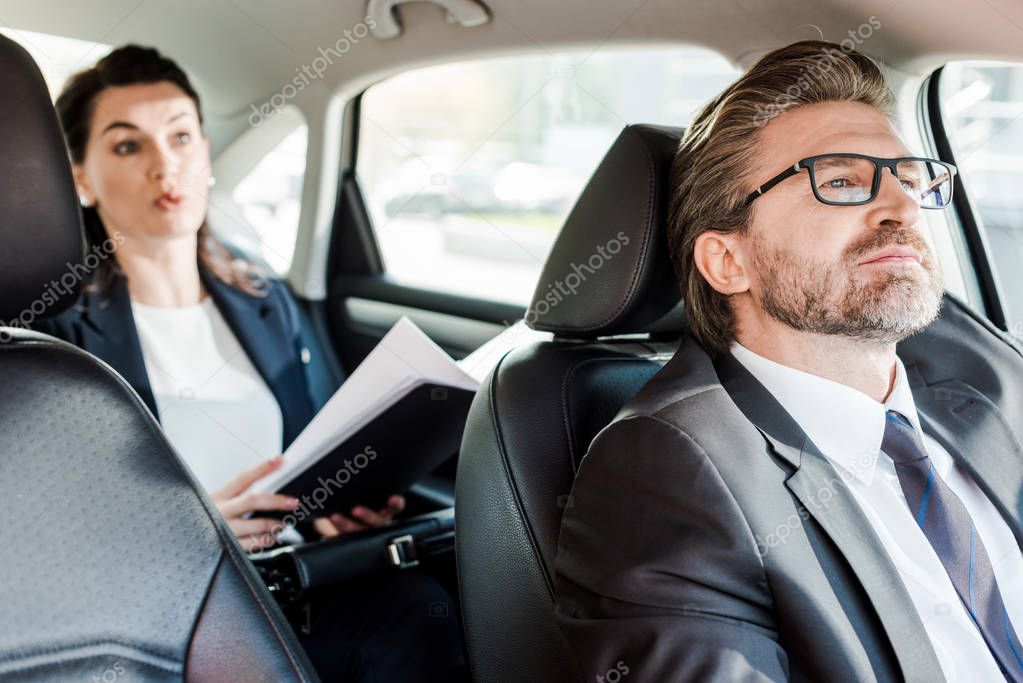 selective focus of bearded diplomat sitting in car with woman 
