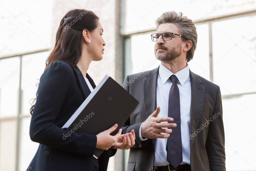 attractive ambassador talking with handsome diplomat in glasses outside 