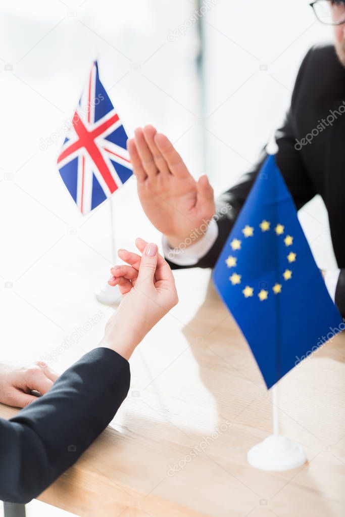 cropped view of diplomat of european union showing money gesture near ambassador of united kingdom