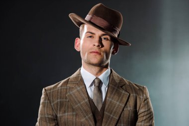 Şapkalı şık gangster, siyah kameraya bakıyor. 