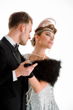 Takım elbiseli şık bir adam ve beyaz tenli aristokrat bir kadın el ele tutuşup dans ediyorlar. 
