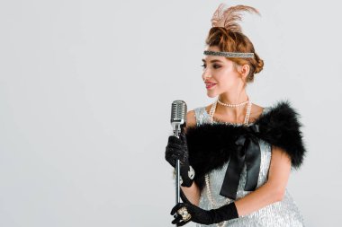 Mutlu şarkıcı beyaz üzerinde izole edilmiş retro mikrofona dokunuyor 