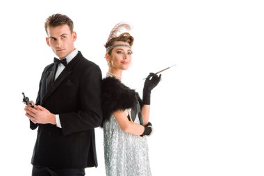 Yakışıklı adam beyaz tenli çekici bir kadının yanında silah tutuyor. 