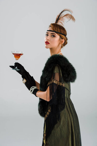 аристократическая женщина держит алкогольный напиток изолирован на серый
 