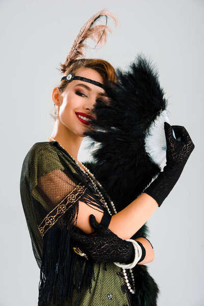 счастливая женщина в черных перчатках держа перо вентилятор изолирован на серый
