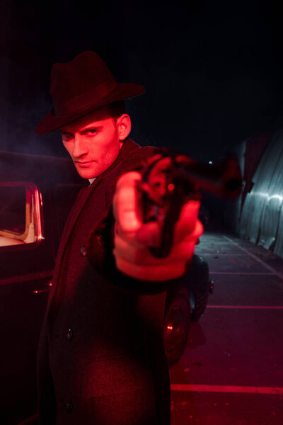 selective focus of handsome man in hat holding gun outside 