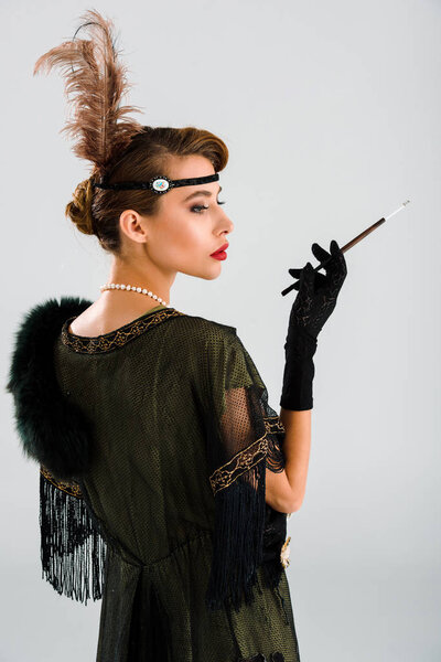 вид сбоку элегантной женщины, держащей держатель на белом
 