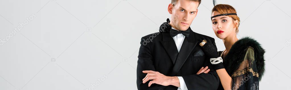 panoramic shot of handsome man in suit standing with aristocratic woman isolated on white