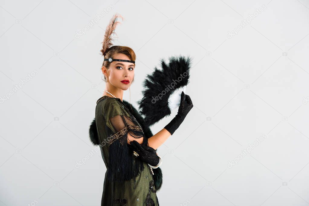aristocratic woman holding black feather fan isolated on grey 