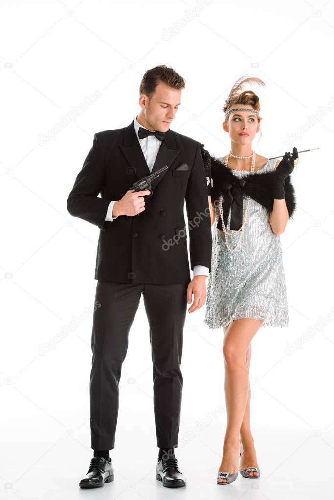 handsome man holding gun near attractive woman with cigarette isolated on white 