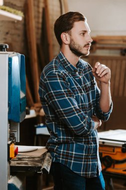 Atölyede duran yakışıklı ve sakallı marangoz. 
