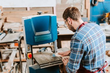 Sakallı ahşap işçisi atölyede cnc makinesi kullanıyor.