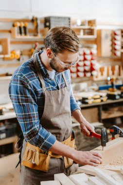 carpenter in goggles holding hammer near wooden dowel  clipart