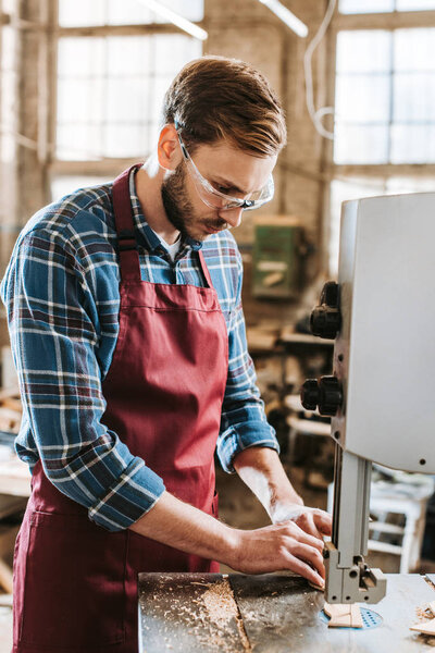 handsome carpenter in goggles using cnc machine 