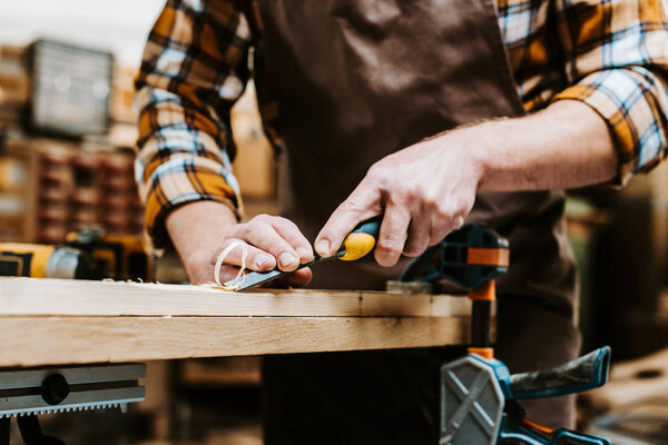 обрезанный вид деревообработчика, держащего зубило во время резки дерева в мастерской
 
