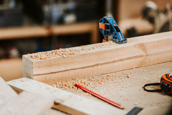selective focus of sawdust on wooden plank near measuring tape 
