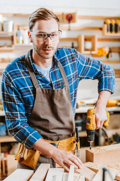 Selective Focus Handsome Woodworker Goggles Holding Hammer Drill Wooden Planks — Stock Photo, Image