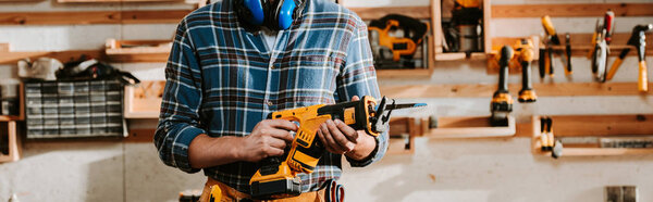 panoramic shot of carpenter holding hammer drill 