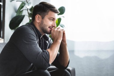 side view of handsome man with panic attack sitting on sofa in apartment 