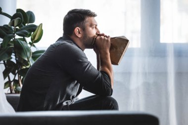 Panik atak geçiren yakışıklı bir adam dairede kağıt torba içinde nefes alıyor. 