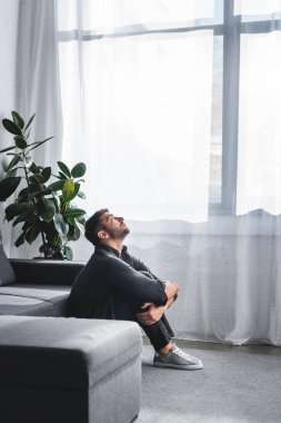 Panik atak geçiren yakışıklı adamın yan görünüşü apartmanda bacakları kucaklaması. 
