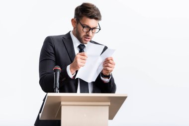 scared businessman in suit standing at podium tribune and rearing paper during conference isolated on white  clipart