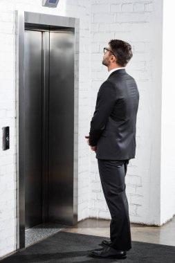 businessman in formal wear waiting for elevator in office  clipart