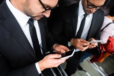 Asansörde akıllı telefon kullanan takım elbiseli iş adamının görüntüsü.