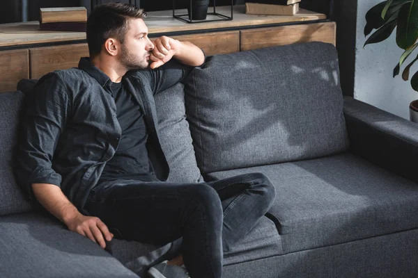 Schöner Und Nachdenklicher Mann Sitzt Auf Sofa Und Schaut Wohnung — Stockfoto