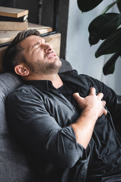 handsome man in shirt having heart attack in apartment 