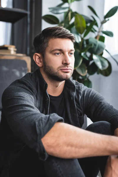 handsome man in black shirt looking away in apartment