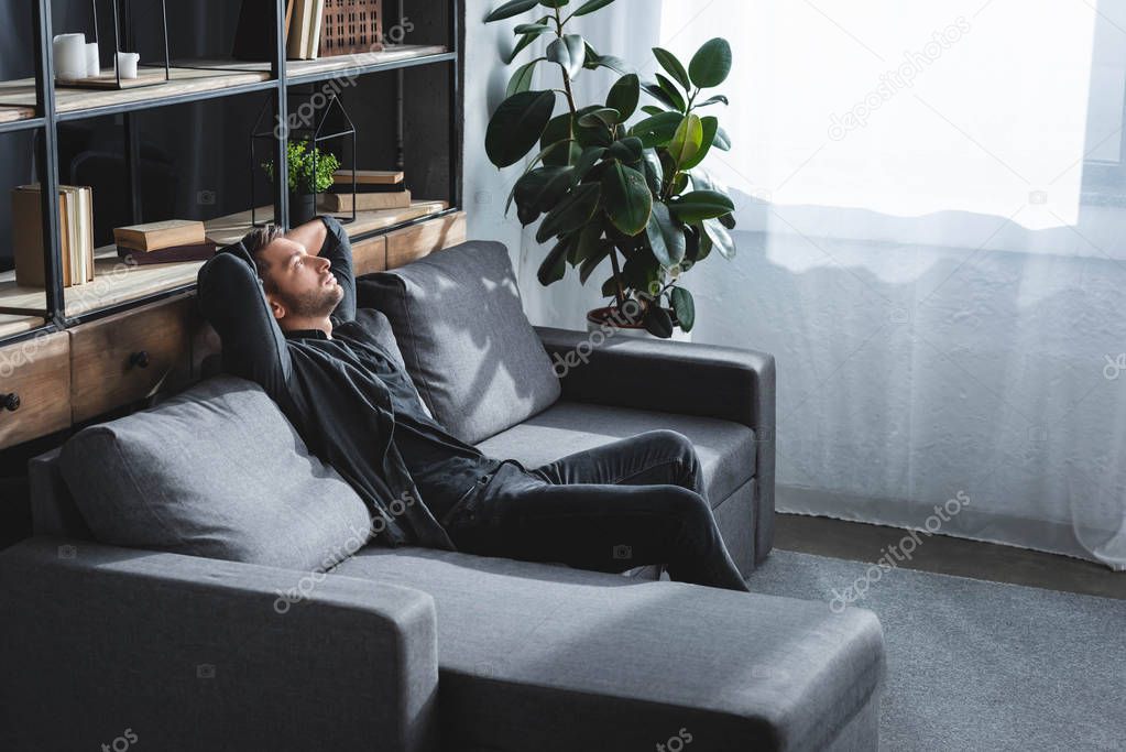 high angle view of handsome man sitting on sofa in apartment 