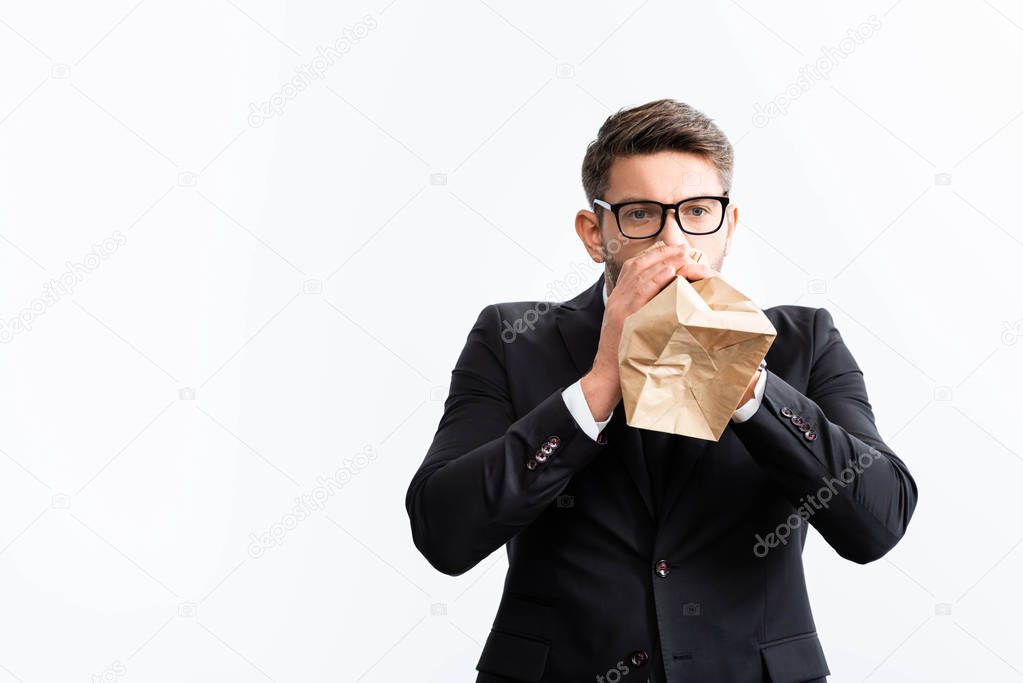 scared businessman in suit breathing in paper bag during conference isolated on white 
