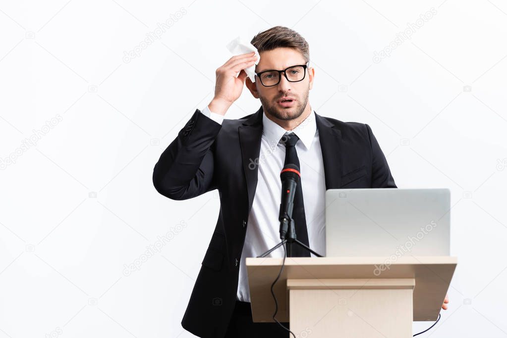 scared businessman in suit standing at podium tribune and holding napkin during conference isolated on white 