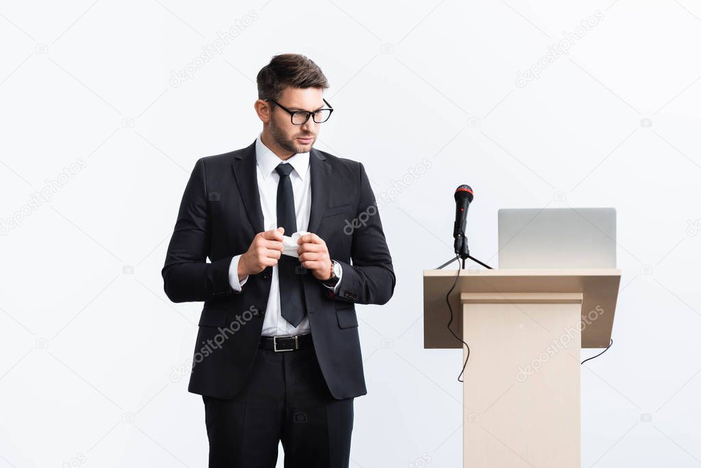 scared businessman in suit standing near podium tribune during conference isolated on white 