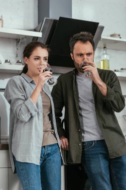 Alkole bağımlı çift mutfakta şarap içiyor.