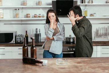 Mutfakta alkol bağımlısı karısıyla tartışan kızgın bir adamın seçici odağı.