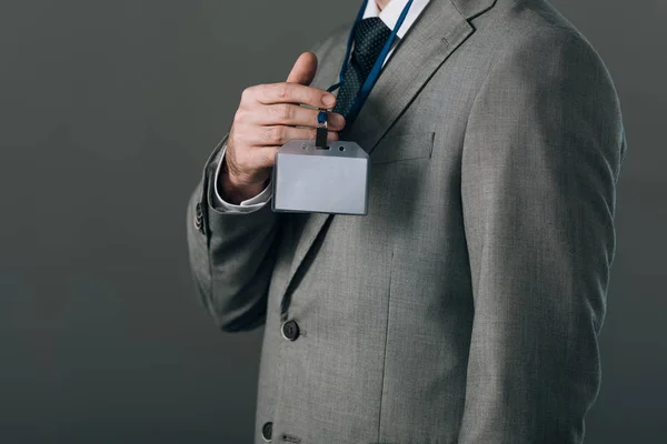 灰色で隔離されたスーツの保持バッジに男の作物のビュー — ストック写真