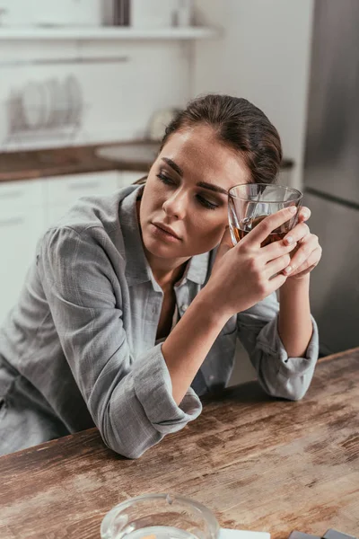 Žena Držící Sklenici Whisky Vedle Popelníku Stole Kuchyni — Stock fotografie