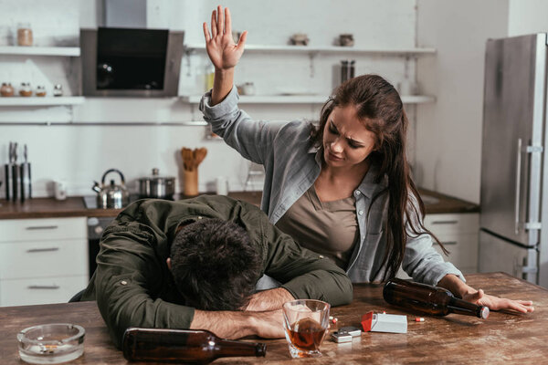 Злая женщина ссорится с пьяным мужем на кухне
