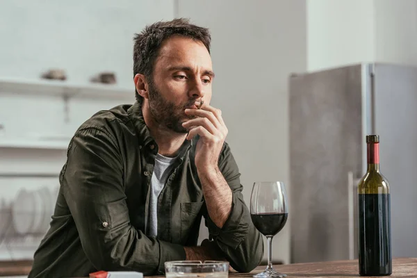 Homme Énervé Fumant Une Cigarette Côté Vin Sur Table — Photo