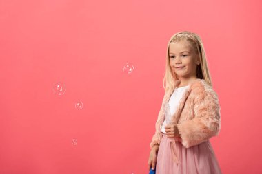 Tatlı ve gülümseyen bir çocuk pembe köpüklü bir şişe tutuyor.