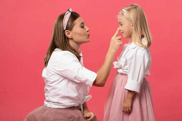 母亲触摸女儿鼻子的侧视图 用粉色隔开 — 图库照片