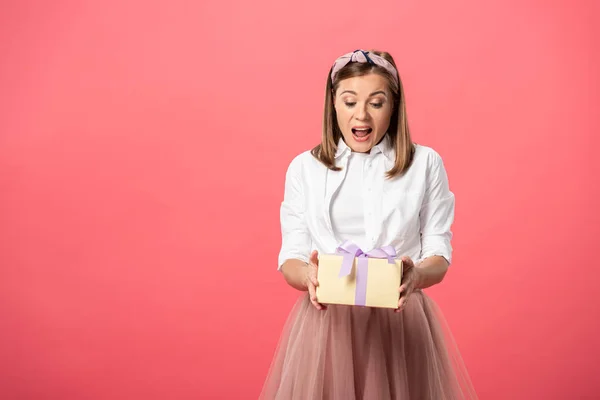 迷人而震惊的女人拿着用粉红隔开的礼品盒 — 图库照片